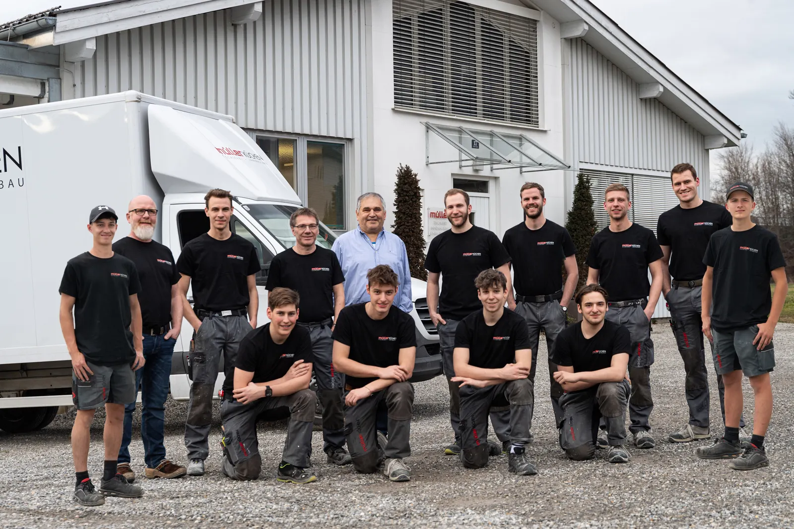 Das Team von Müller Küchen in schwarzen Firmen-Shirts vor der Werkstatt in Altach