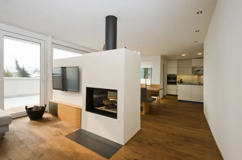 Wohnraum mit Kamin-Raumteiler und Eichenbank